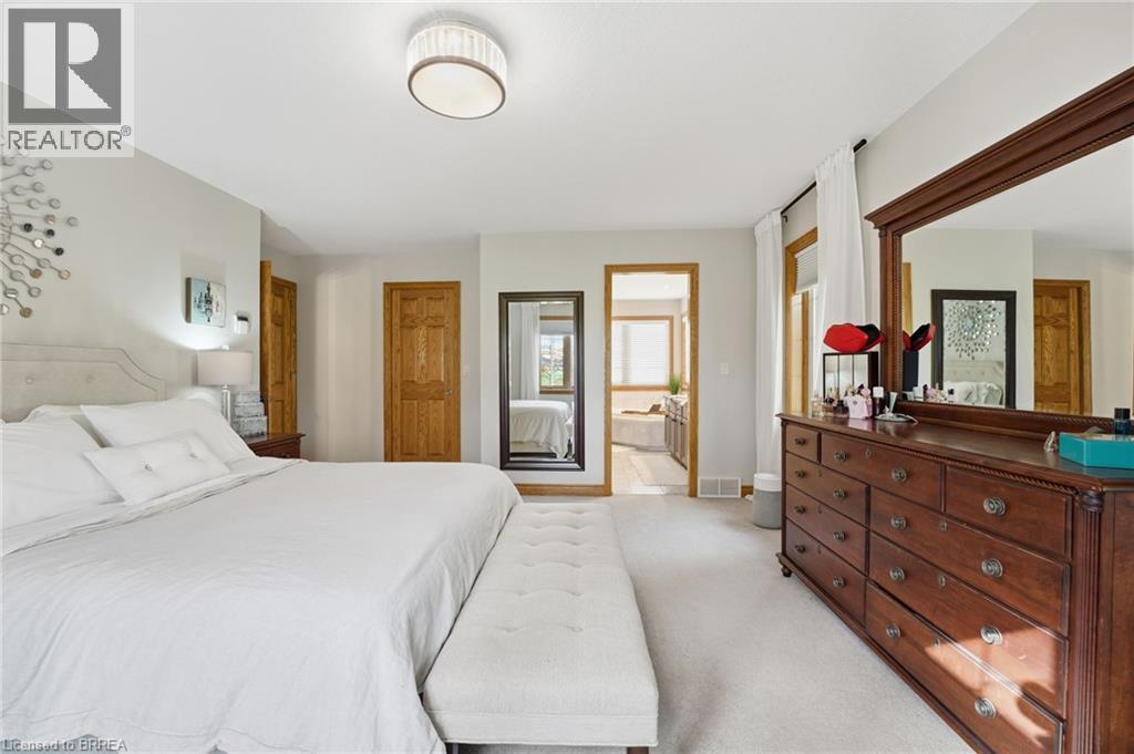 Carpeted bedroom featuring light gray walls, a white upholstered headboard, and wood-finish doors - 271 Windham Rd 14, Simcoe, ON