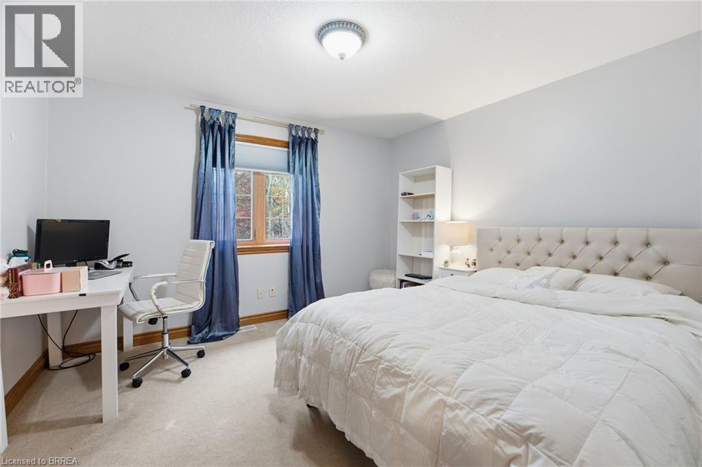 Carpeted bedroom featuring a window with wood trim, a ceiling-mounted light fixture, and light-colored walls - 271 Windham Rd 14, Simcoe, ON