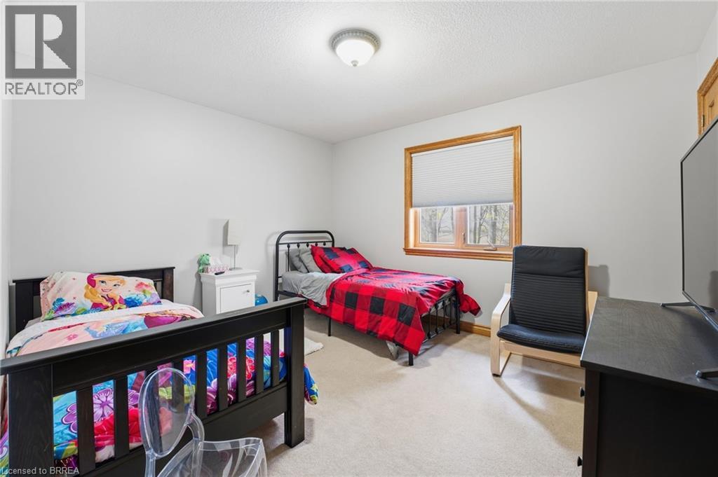 Bedroom featuring light neutral walls, carpet flooring, a window with wood trim, and a flush mount ceiling light fixture - 271 Windham Rd 14, Simcoe, ON