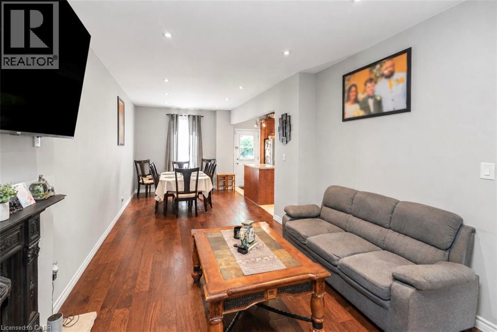 Open-concept living and dining area featuring wood-finish flooring, recessed lighting, and light gray wall tones - 38 Fairleigh Avenue N, Hamilton, ON