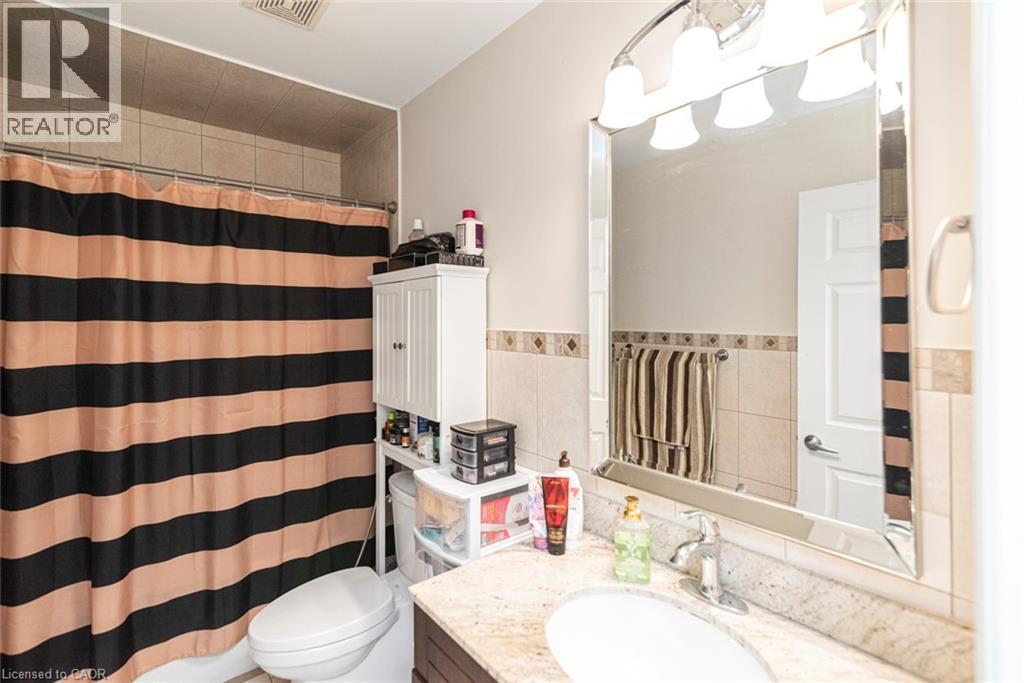 Bathroom featuring a vanity with a light-colored countertop and undermount sink, a framed mirror, and a chrome light fixture - 38 Fairleigh Avenue N, Hamilton, ON