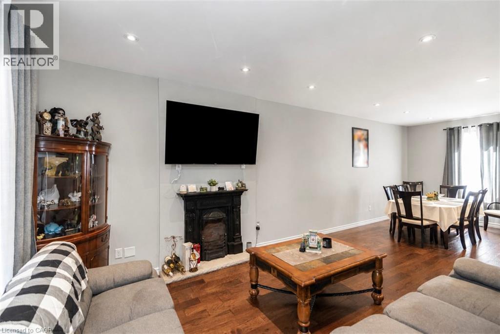 Open-concept living area featuring hardwood flooring, recessed lighting, a decorative fireplace with a black mantel, and a dining area with window treatments - 38 Fairleigh Avenue N, Hamilton, ON