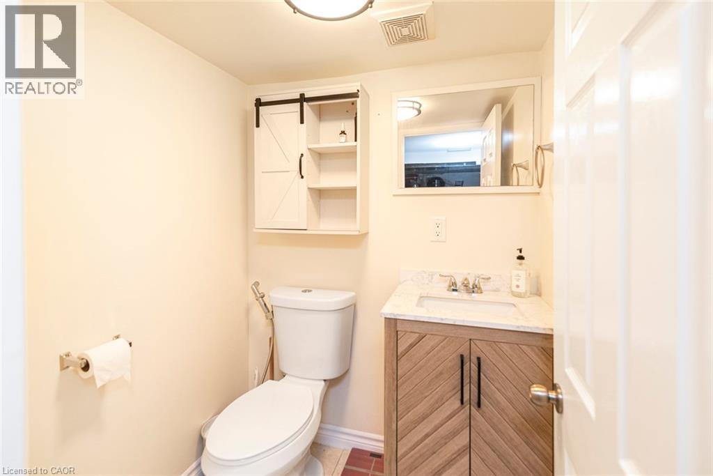 Bathroom featuring a floating vanity with a marble-finish countertop, undermount sink, and a modern barn door-style medicine cabinet with open shelving - 38 Fairleigh Avenue N, Hamilton, ON