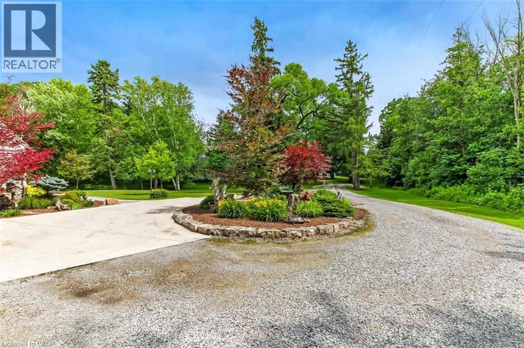 Beautifully landscaped, gravel driveway with cement portion adjacent to house. - 59 Decou Road, Simcoe, ON
