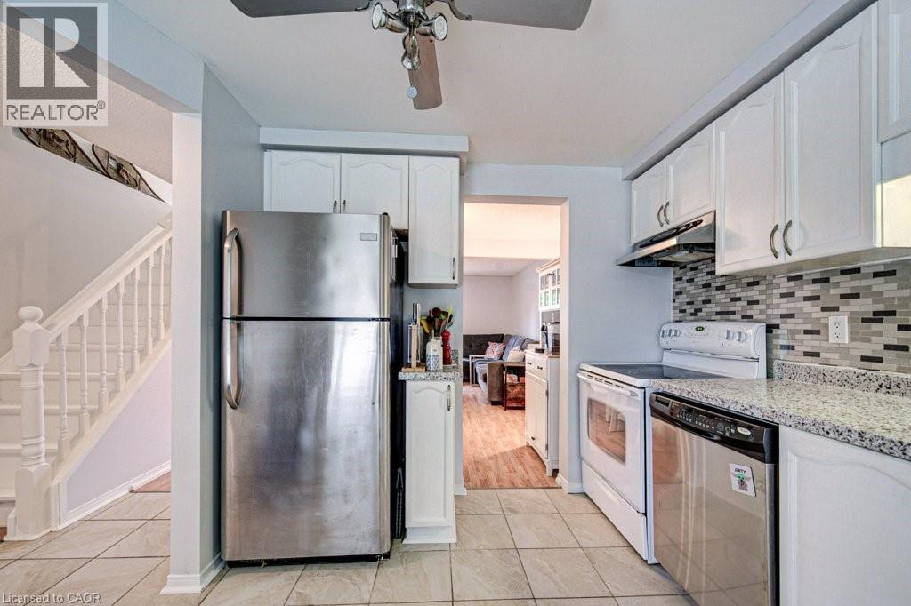 Kitchen featuring white cabinetry, stone-finish countertops, and a mosaic tile backsplash - 854 Elgin Street N, Cambridge, ON