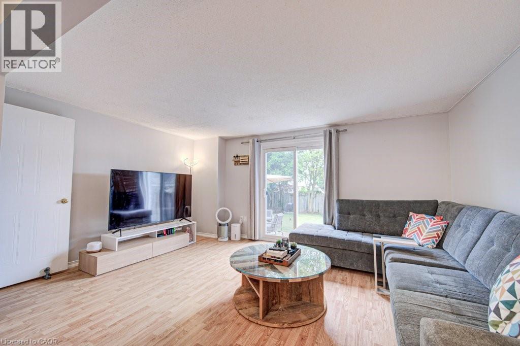 Living area featuring wood-finish flooring, light-toned walls, and a sliding glass door leading to the backyard - 854 Elgin Street N, Cambridge, ON