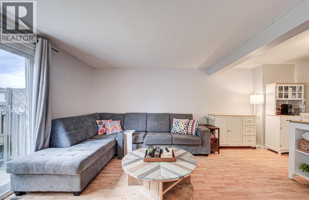 Spacious living area featuring wood-finish flooring, light-toned walls, and a sliding glass door providing exterior access - 854 Elgin Street N, Cambridge, ON