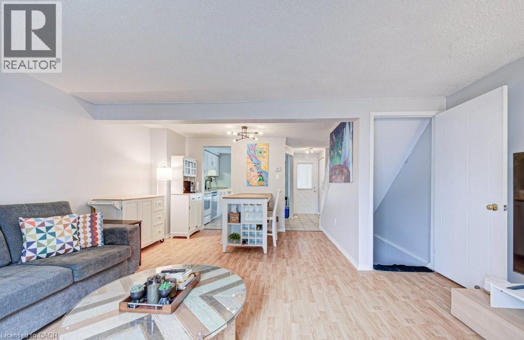 Open-concept living area featuring light wood-finish flooring, white walls, and a recessed staircase entrance - 854 Elgin Street N, Cambridge, ON