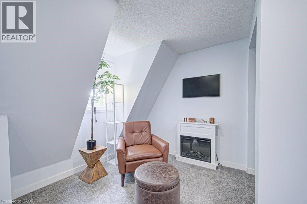 Sloped ceiling room featuring a window with natural light, textured ceiling, light-colored walls, and gray carpet flooring - 854 Elgin Street N, Cambridge, ON