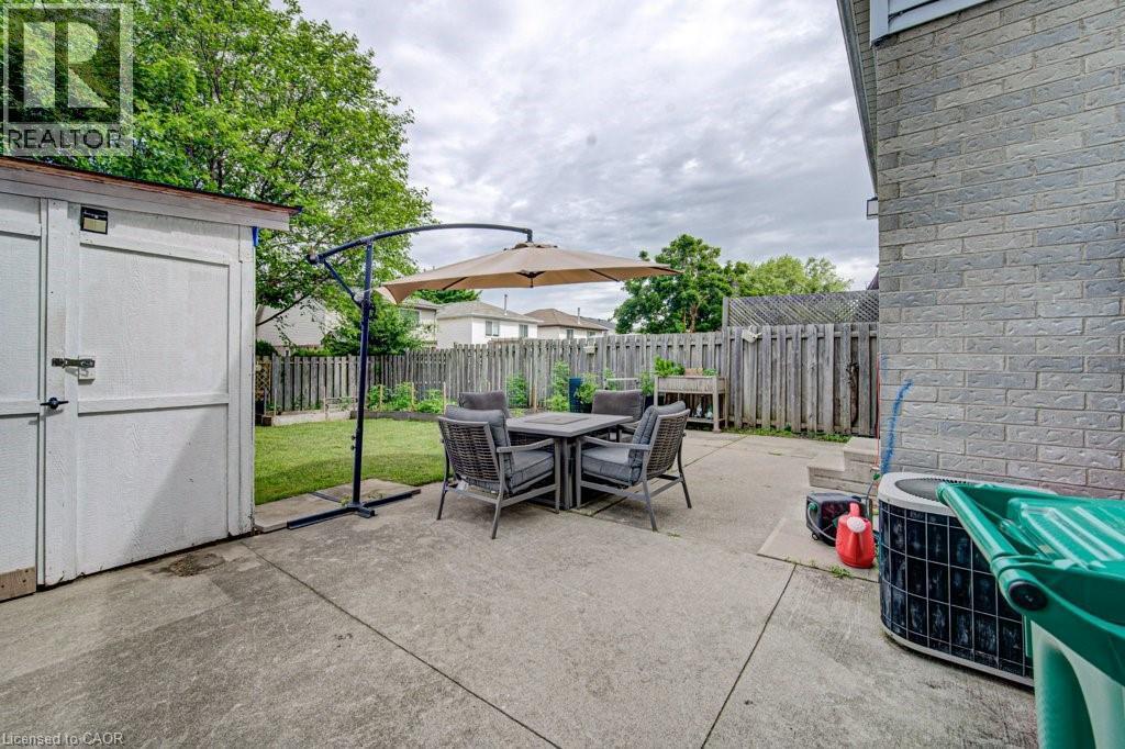 Expansive concrete patio area with a wooden privacy fence - 854 Elgin Street N, Cambridge, ON