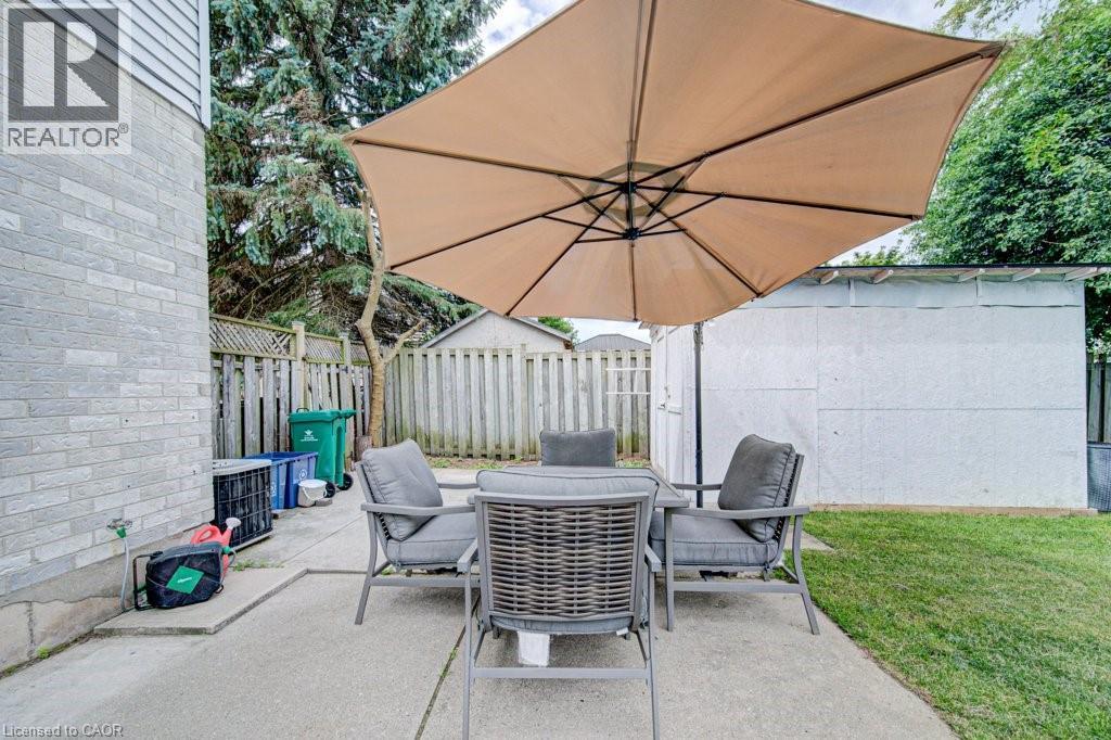 Concrete patio area featuring a grass lawn, privacy fencing, and a storage shed - 854 Elgin Street N, Cambridge, ON