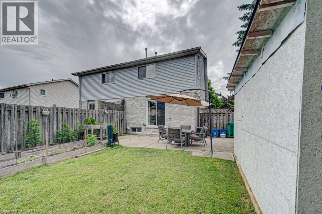 Spacious backyard featuring a manicured lawn, a large concrete patio, and built-in raised garden beds - 854 Elgin Street N, Cambridge, ON