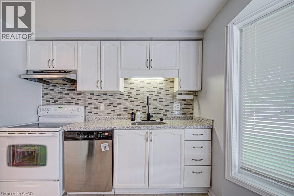 Kitchen featuring white cabinetry, a mosaic tile backsplash, and light-toned countertops - 854 Elgin Street N, Cambridge, ON