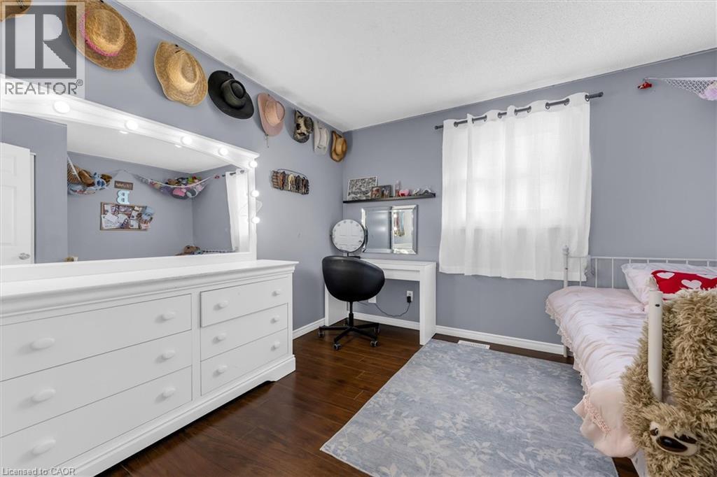 Bedroom featuring wood-finish flooring, light gray wall color, and a window with white drapery - 338 East 24Th Street, Hamilton, ON