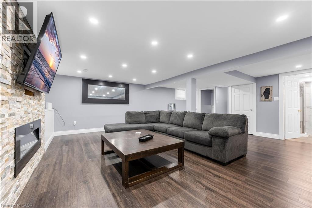 Spacious living area featuring wood-finish flooring, recessed lighting, and a stone-accented wall with an integrated electric fireplace - 338 East 24Th Street, Hamilton, ON