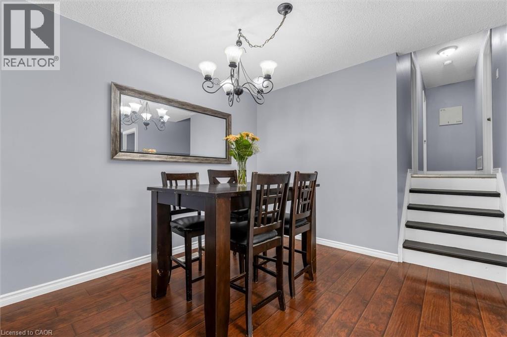 Dining area featuring wood-finish flooring, a contemporary chandelier, and a decorative framed mirror - 338 East 24Th Street, Hamilton, ON