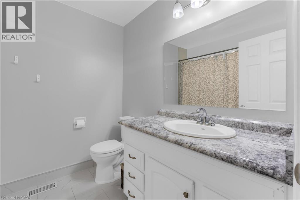 Bathroom featuring a vanity with an oval undermount sink, chrome faucet, and a stone-finish countertop - 338 East 24Th Street, Hamilton, ON