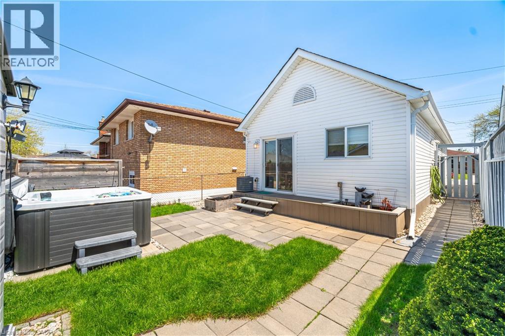 Expansive backyard featuring a hot tub, patio space, and a manicured lawn - 71 Beland Avenue N, Hamilton, ON - Outdoor With Exterior
