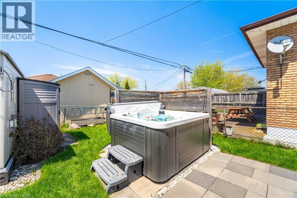 Backyard featuring an outdoor spa with composite steps, paver patio, and a section of manicured lawn - 71 Beland Avenue N, Hamilton, ON - Outdoor With Exterior