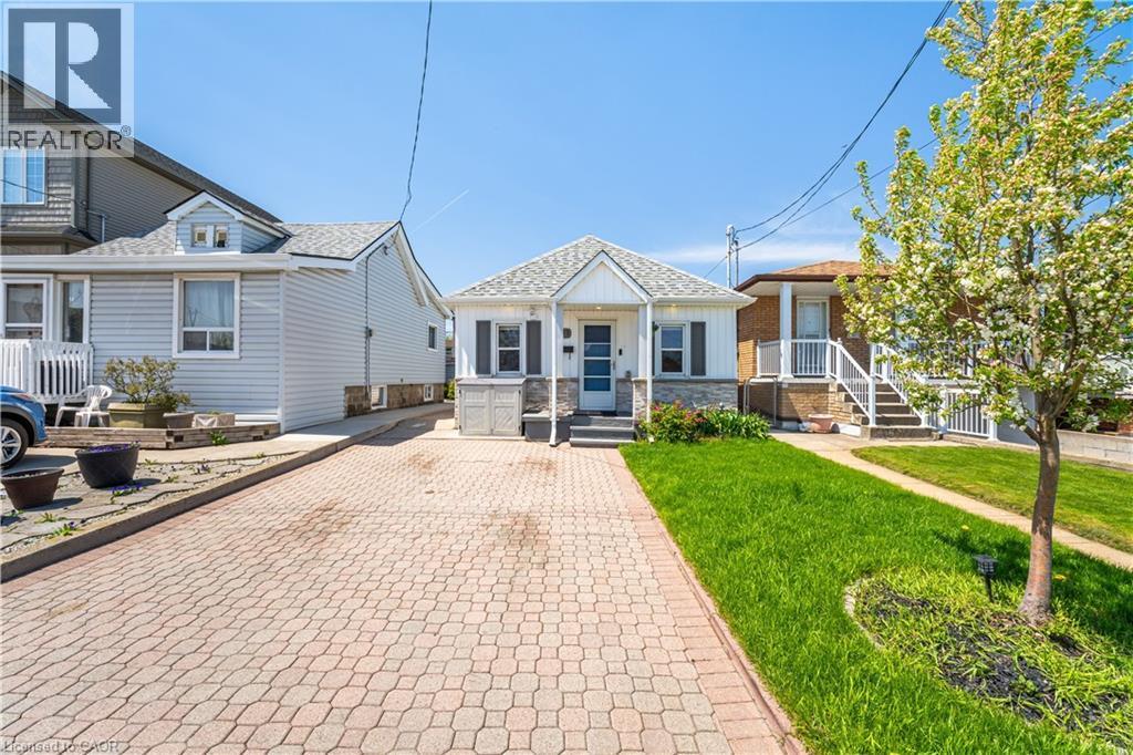 White siding residence featuring a gabled roofline, stone veneer accents, and a covered porch - 71 Beland Avenue N, Hamilton, ON - Outdoor With Facade
