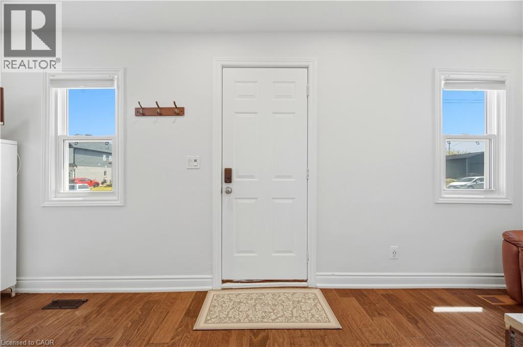 Entryway with a paneled white door, wood-finish flooring, and two double-hung windows - 71 Beland Avenue N, Hamilton, ON - Indoor Photo Showing Other Room