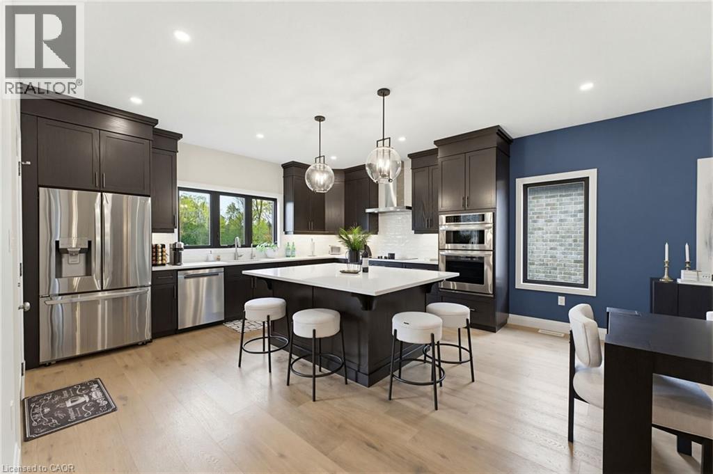 Modern kitchen featuring dark wood cabinetry, stainless steel appliances, and light wood-finish flooring - 37 Gilmer Crescent, Listowel, ON - Indoor