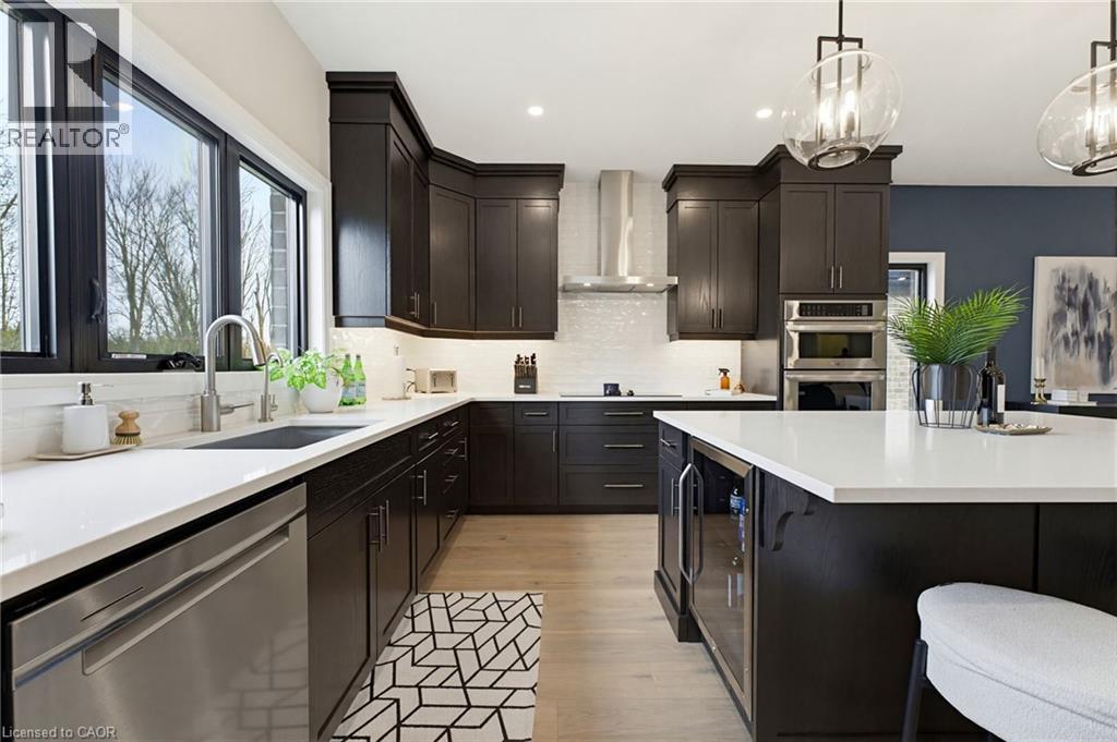 Contemporary kitchen featuring dark wood cabinetry, white countertops, stainless steel appliances, and wood-finish flooring - 37 Gilmer Crescent, Listowel, ON - Indoor Photo Showing Kitchen With Upgraded Kitchen