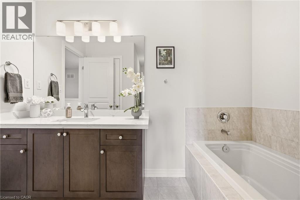 Bathroom vanity featuring a single sink, dark wood-finish cabinetry with white knob hardware, and a white countertop - 4171 Palermo Common, Burlington, ON - Indoor Photo Showing Bathroom