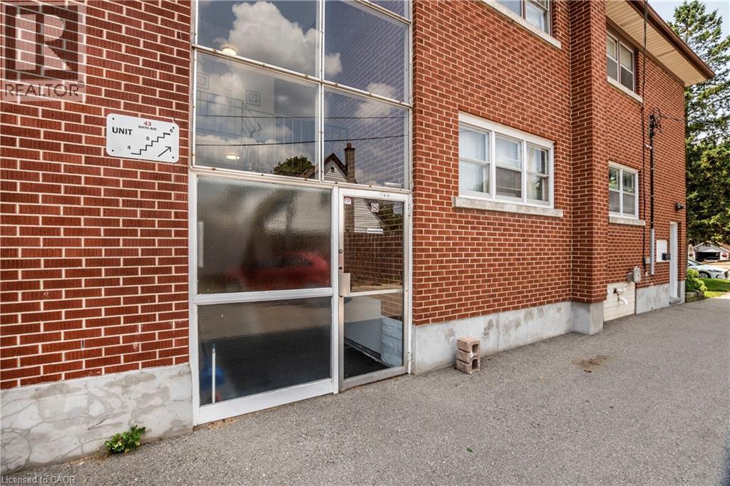 Red brick exterior with multiple windows, a glass-paneled entrance, and a concrete foundation - 43 Sixth Avenue, Kitchener, ON - Outdoor With Exterior