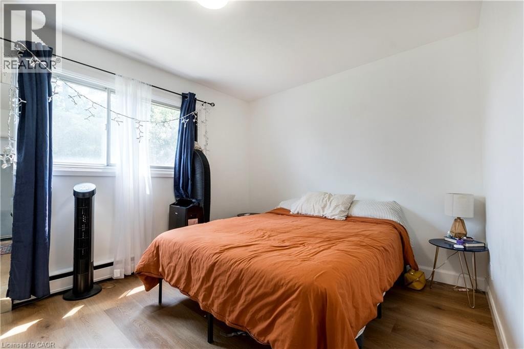 Bright room featuring wood-finish flooring, white walls, and a window with a baseboard heater below - 43 Sixth Avenue, Kitchener, ON - Indoor Photo Showing Bedroom