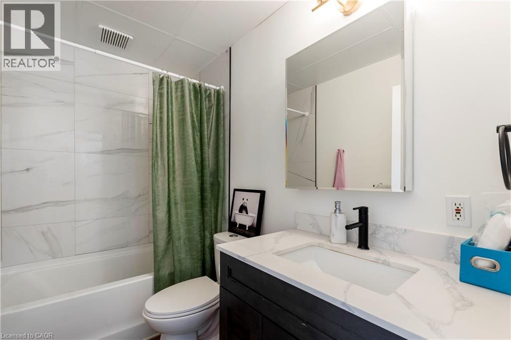 Bathroom featuring a white bathtub, large format wall tiles with subtle veining, and a dark wood-finish vanity with an integrated rectangular sink - 43 Sixth Avenue, Kitchener, ON - Indoor Photo Showing Bathroom
