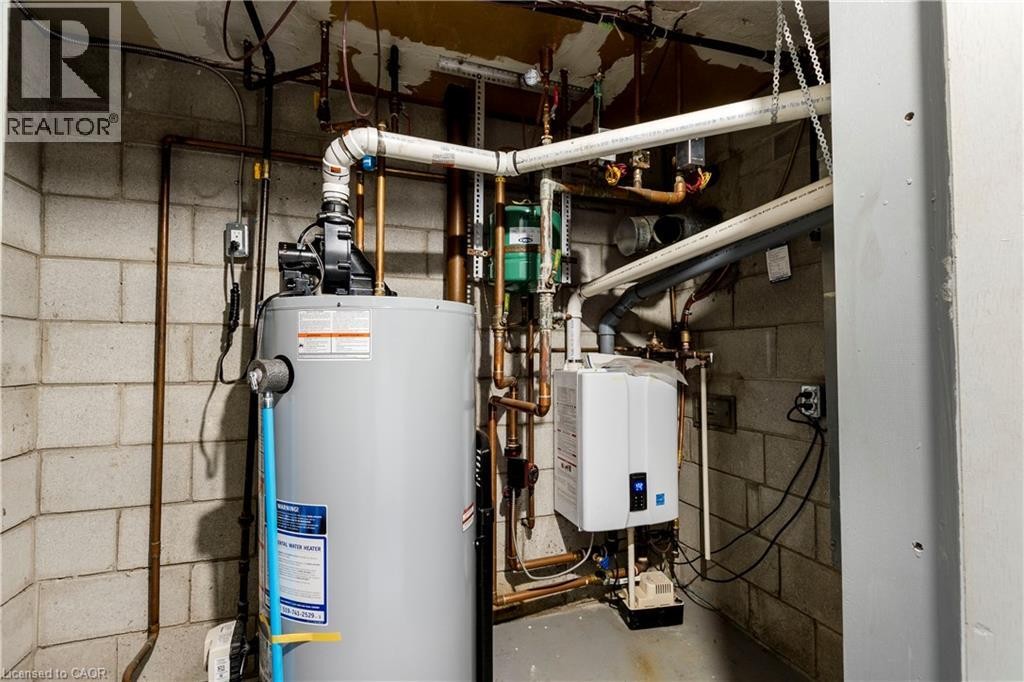 Utility space featuring a tank water heater, a tankless water heater, and extensive copper and PVC plumbing - 43 Sixth Avenue, Kitchener, ON - Indoor Photo Showing Basement