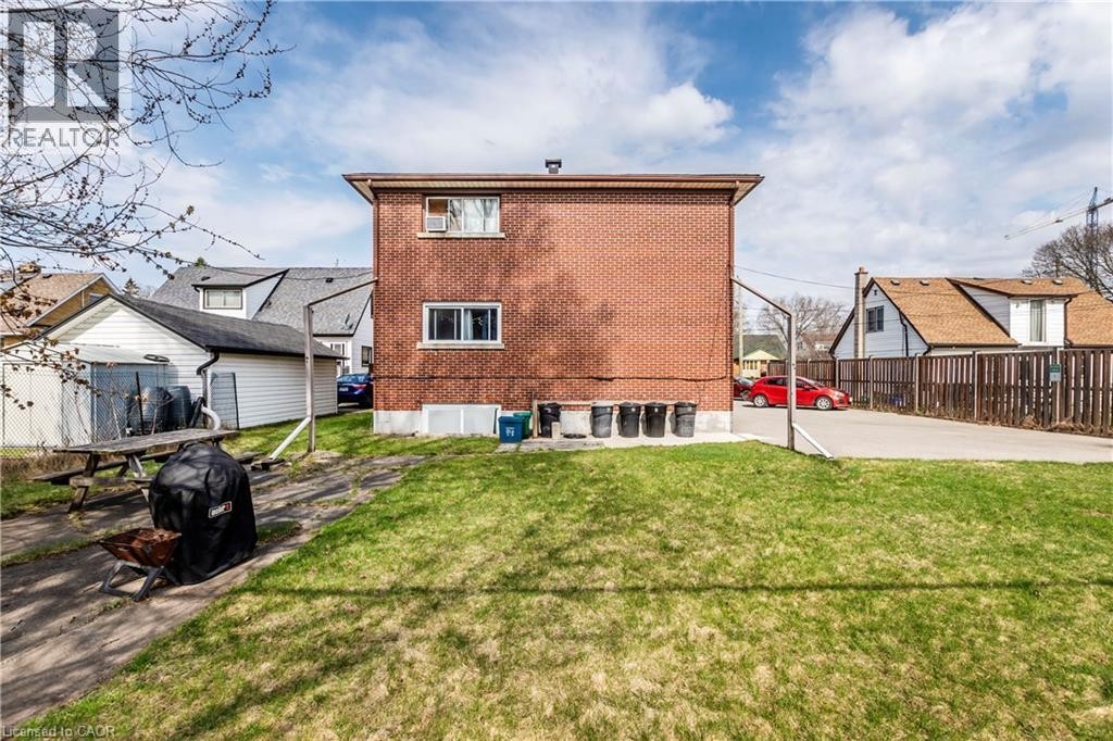 Expansive backyard featuring a manicured lawn, brick exterior, multiple windows, and a detached garage - 43 Sixth Avenue, Kitchener, ON - Outdoor With Exterior