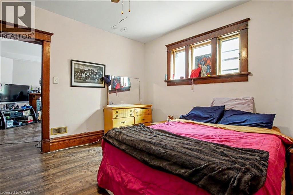 Main Floor Bedroom featuring wood-finish flooring, a window with wood trim, and a doorway with wood casing - 30 Hohner Avenue, Kitchener, ON - Indoor Photo Showing Bedroom