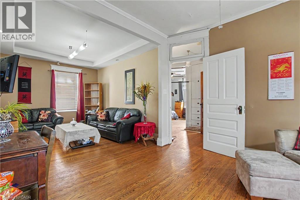 Living area with wood-finish flooring, tray ceiling, and a prominent doorway featuring an overhead transom window - 30 Hohner Avenue, Kitchener, ON - Indoor Photo Showing Living Room