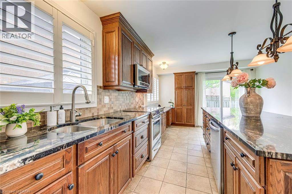 Kitchen featuring wood cabinetry, dark stone countertops, stainless steel appliances, and a tiled backsplash - 43 Niska Drive, Waterdown, ON - Indoor Photo Showing Kitchen With Double Sink With Upgraded Kitchen