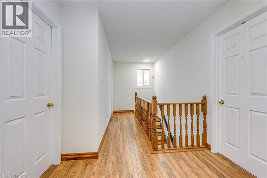 Hallway featuring wood-finish flooring, white paneled doors with brass hardware, and a wood banister - 43 Niska Drive, Waterdown, ON - Indoor Photo Showing Other Room