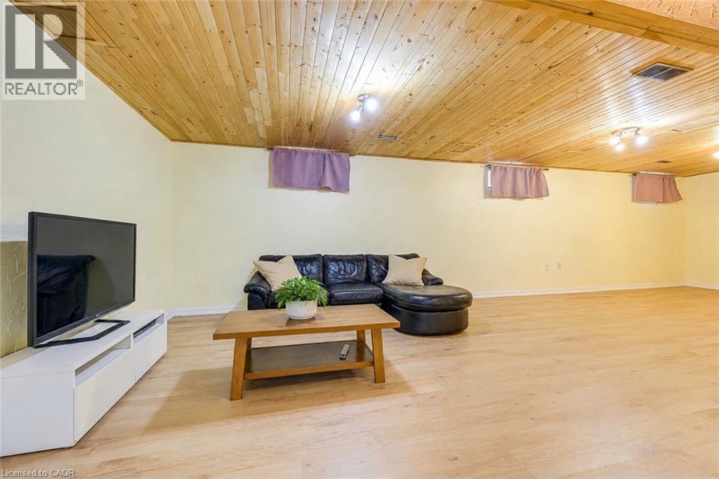 Spacious room featuring light-colored wood-finish flooring, a wood-paneled ceiling with track lighting, and soft yellow wall paint - 43 Niska Drive, Waterdown, ON - Indoor