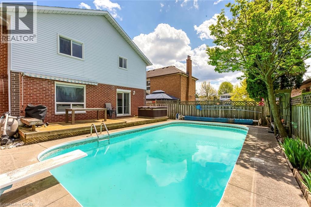 Private backyard featuring an in-ground swimming pool with concrete surround, a diving board, and a wooden deck - 43 Niska Drive, Waterdown, ON - Outdoor With In Ground Pool With Deck Patio Veranda