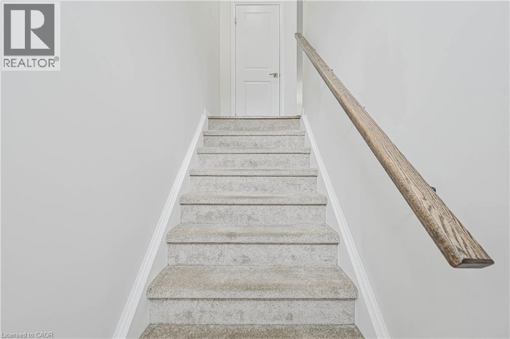 Carpeted staircase with a wood-finish handrail and crisp white trim - 720 Grey Street Unit# 34, Brantford, ON - Indoor Photo Showing Other Room