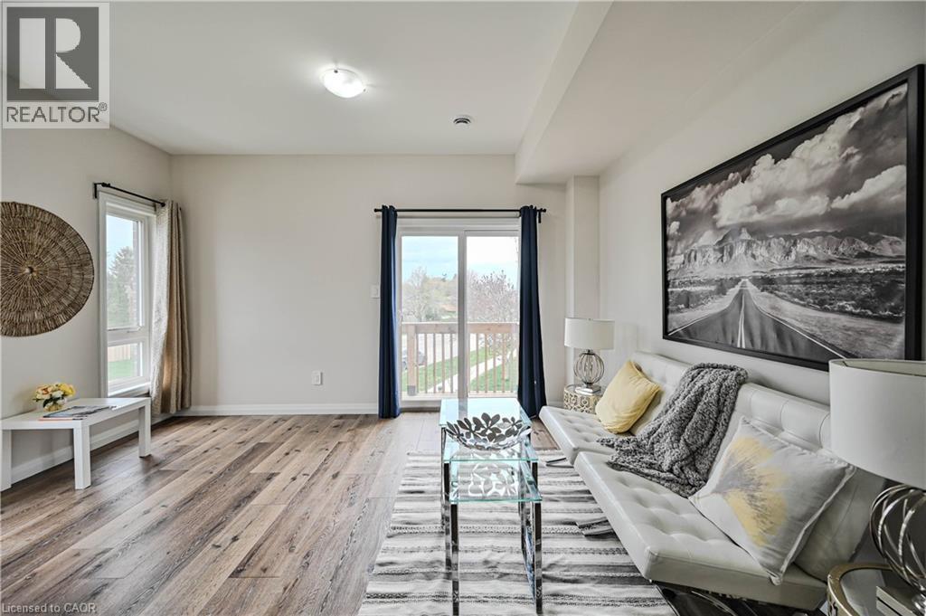 Spacious living area featuring wood-finish flooring, light-toned walls, and a large window - 720 Grey Street Unit# 34, Brantford, ON - Indoor
