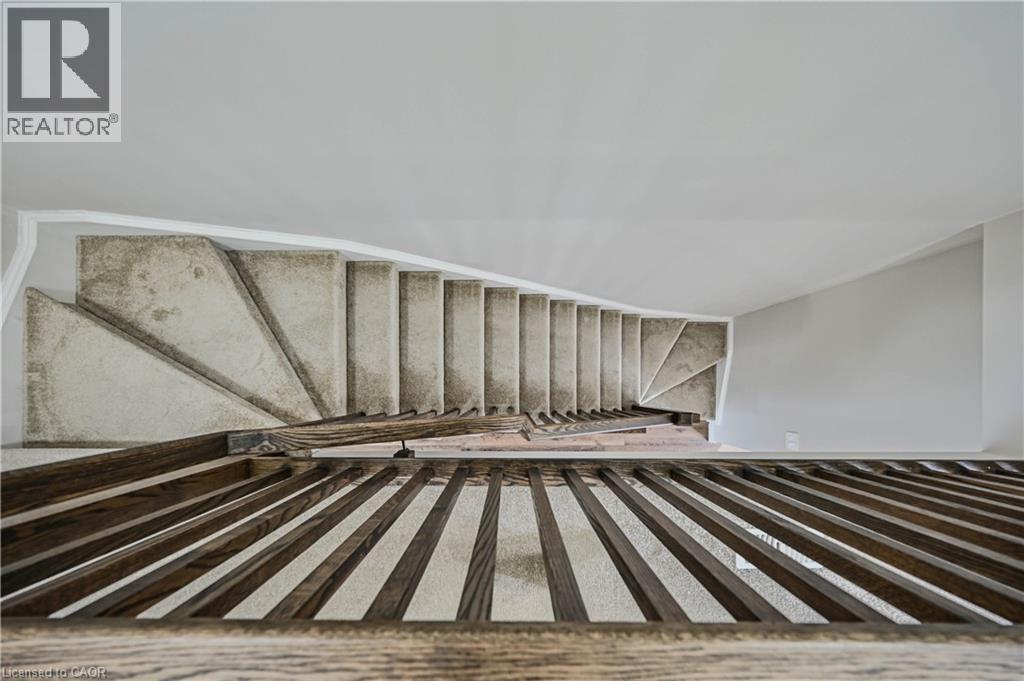 Carpeted staircase with dark wood-finish railing and balusters - 720 Grey Street Unit# 34, Brantford, ON - Indoor Photo Showing Other Room