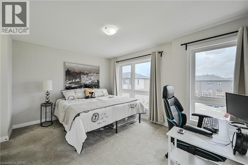 Carpeted bedroom featuring multiple windows, light neutral wall paint, and a flush mount ceiling light fixture - 720 Grey Street Unit# 34, Brantford, ON - Indoor Photo Showing Bedroom