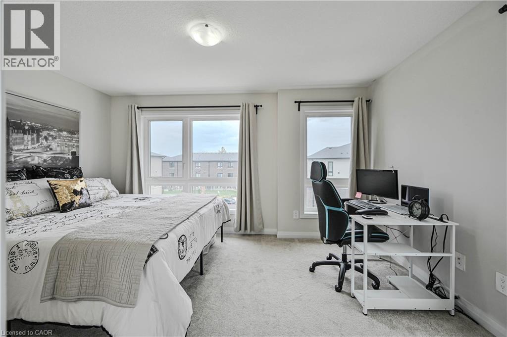 Spacious bedroom featuring light-toned carpeting and multiple windows for abundant natural light - 720 Grey Street Unit# 34, Brantford, ON - Indoor Photo Showing Bedroom