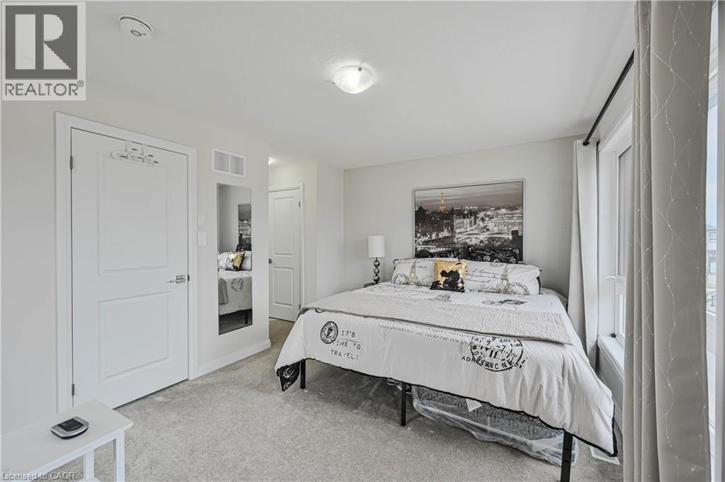 Carpeted room featuring a double-pane window with vertical blinds, a flush-mount ceiling light fixture, and a built-in recessed mirror - 720 Grey Street Unit# 34, Brantford, ON - Indoor Photo Showing Bedroom