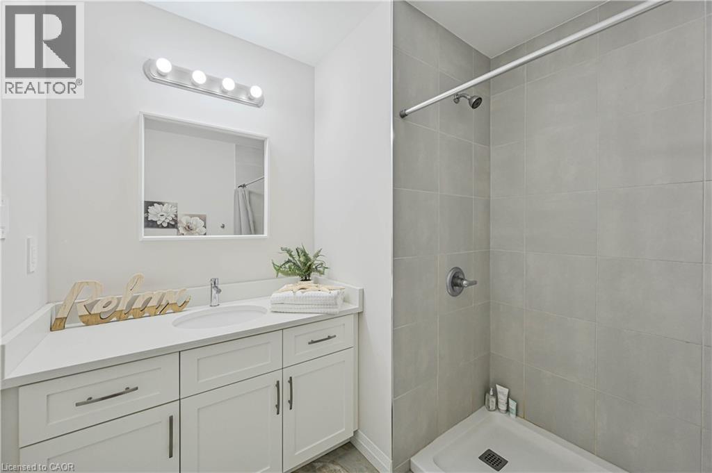 Bathroom featuring a white vanity with shaker-style cabinetry, a built-in sink, and a rectangular mirror - 720 Grey Street Unit# 34, Brantford, ON - Indoor Photo Showing Bathroom