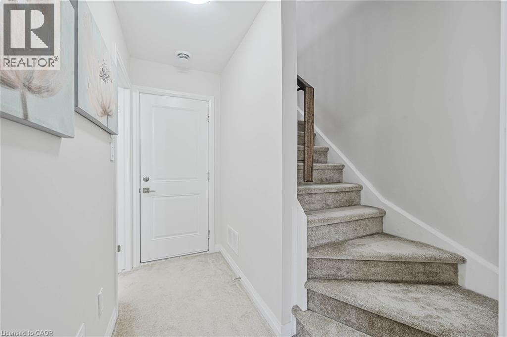 Carpeted staircase featuring a wood-finish handrail - 720 Grey Street Unit# 34, Brantford, ON - Indoor Photo Showing Other Room