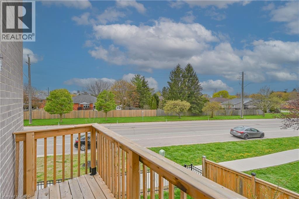 Wood-plank balcony with natural wood railings, overlooking a paved road and sidewalk - 720 Grey Street Unit# 34, Brantford, ON - Outdoor With View