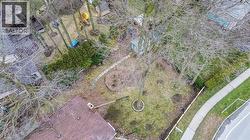 Spacious property featuring mature trees, a stone pathway, a side yard with landscaping, and a partial view of a shingled roofline -