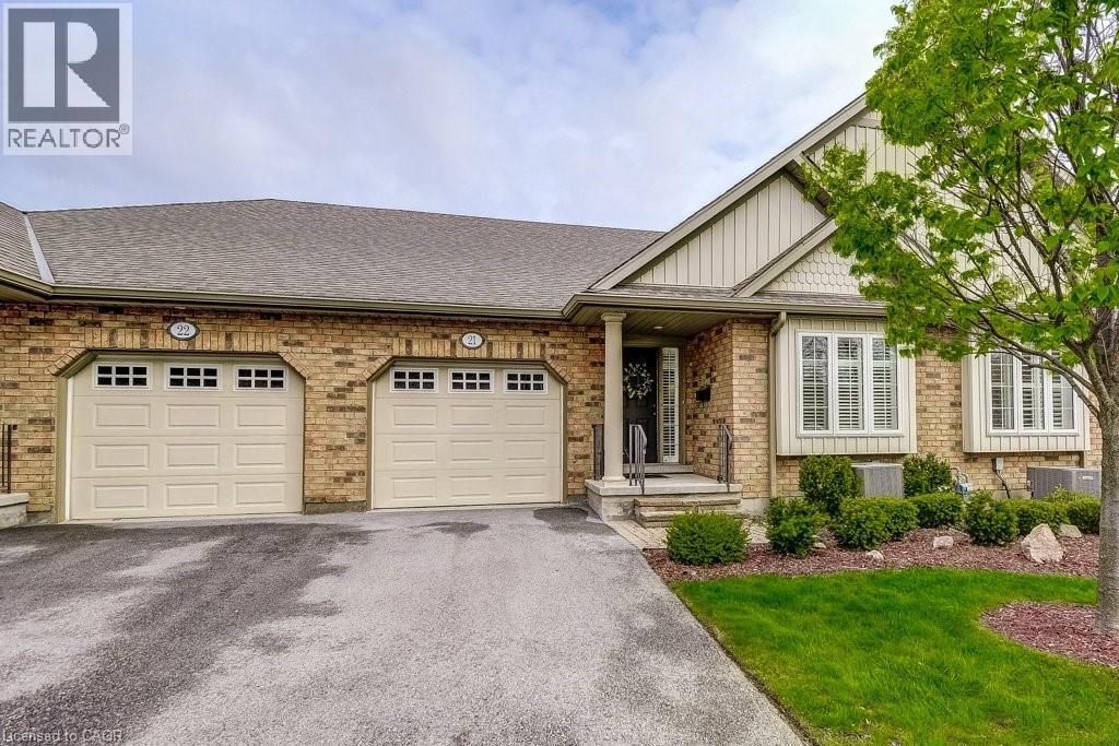 Brick exterior featuring two garage bays with paneled doors and window accents - 605 Welland Avenue Unit# 21, St. Catharines, ON - Outdoor With Facade